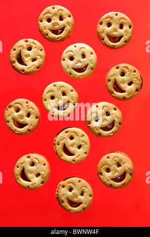 Smiling cookies filled with jam isolated on red background Stock Photo