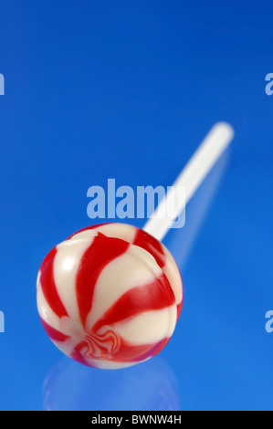 Colorful red white stripy lollipop isolated on blue background Stock Photo