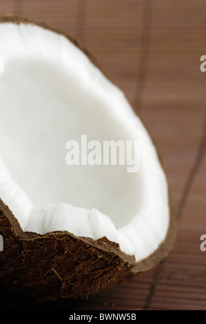 Closeup of a cracked coconut cracked on brown background Stock Photo