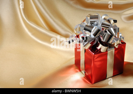 Red gift box with a silver bow on golden background