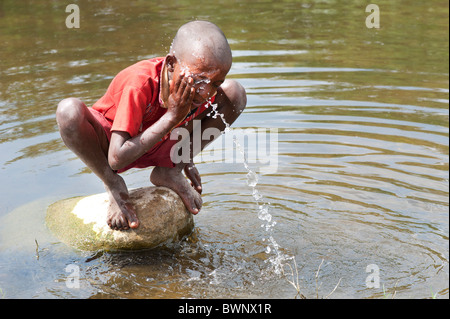 Indian street boy washing himself and drinking water in a river in the ...