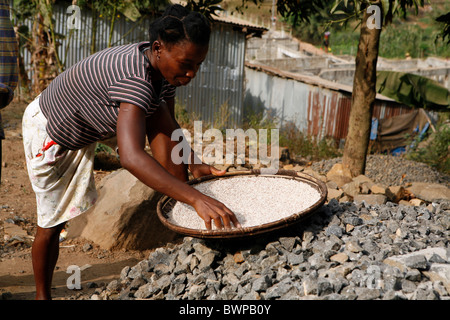 woman sorts stones that have been broken to sell for construction in Freetown Sierra Leone West Africa Stock Photo