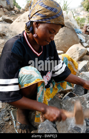 woman breaking stones Freetown Sierra Leone West Africa to sell. The broken stones are in the construction industry Stock Photo