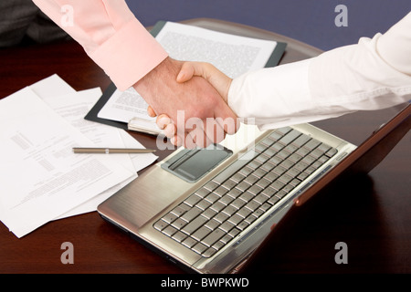 Photo of handshake of business partners after striking deal on background of laptop and documents Stock Photo