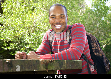 African American student wearing backpack sitting at outdoor table Stock Photo