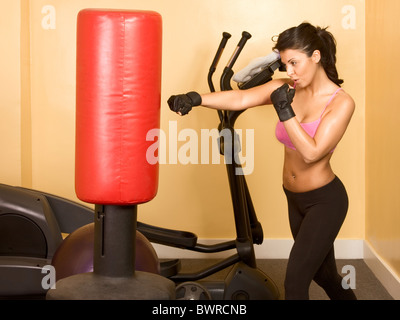 Attractive woman kickboxing with red punching bag Stock Photo