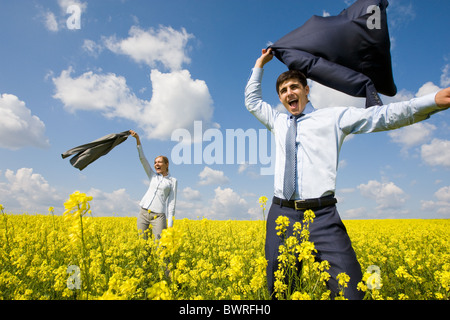 Portrait of happy business partners happily screaming in yellow meadow Stock Photo