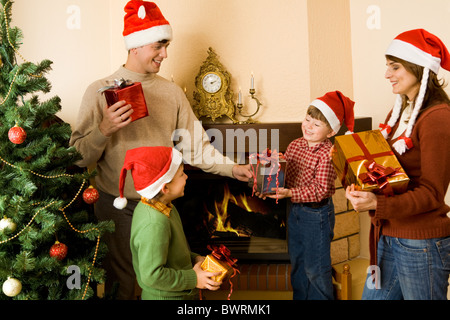 Portrait of parents and sons wearing santa hats with presents in hands Stock Photo