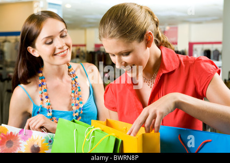 Photo of two friends looking through their shoppings with smiles in the mall Stock Photo