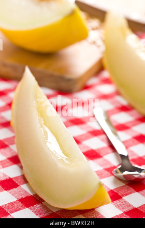 cut honeydew melon on checkered tablecloth Stock Photo