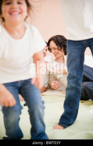 Parents watching daughters jumping on bed Stock Photo