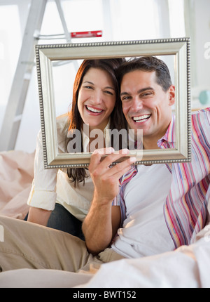 Smiling couple looking through empty frame Stock Photo