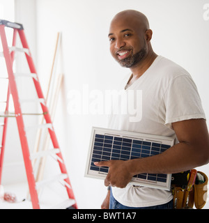 African American construction worker carrying solar panel Stock Photo
