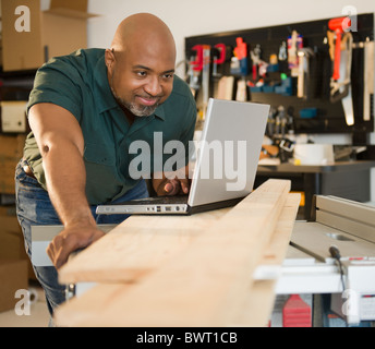 African American carpenter using laptop in workshop Stock Photo