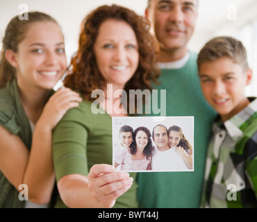 Hispanic woman with family holding out family portrait