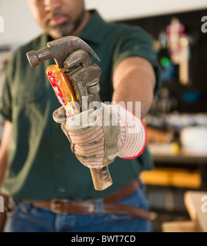 African American carpenter holding screwdriver, wrench and hammer Stock Photo