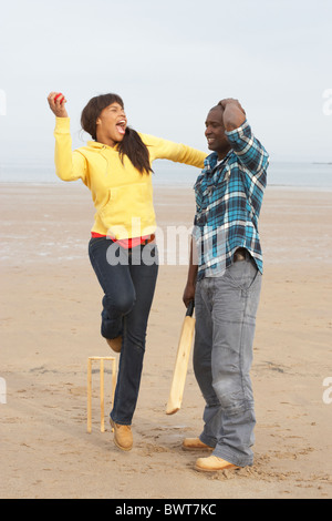Young Couple Playing Cricket On Autumn Beach Holiday Stock Photo