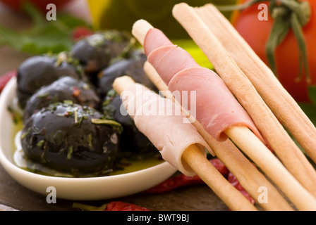 Grissini with ham and pickled black olive ar closeup on wood Stock Photo