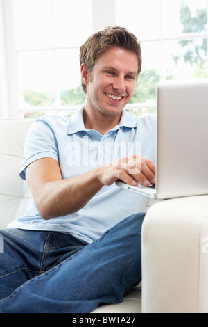 Man Sitting On Sofa Using Laptop At Home Stock Photo