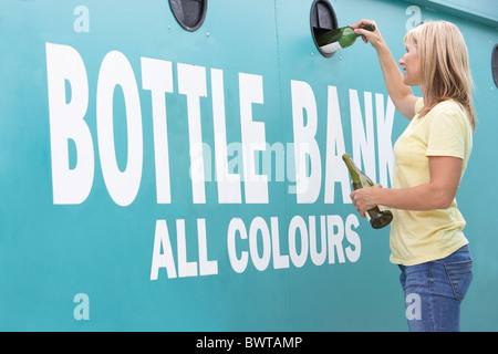 Woman At Recycling Centre Disposing Of Glass At Bottle Bank Stock Photo