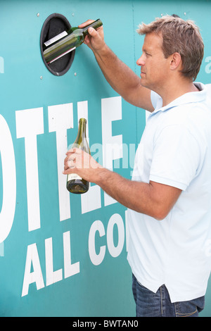 Man At Recycling Centre Disposing Of Glass At Bottle Bank Stock Photo