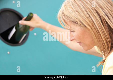 Woman At Recycling Centre Disposing Of Glass At Bottle Bank Stock Photo