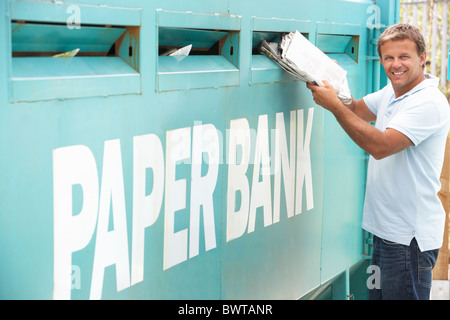 Man At Recycling Centre Disposing Of Old Newspapers Stock Photo