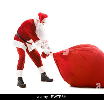 Portrait of happy Santa carrying heavy big red sack with presents Stock Photo