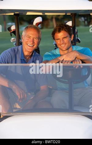 Two Male Golfers Riding Golf Buggy On Golf Course Stock Photo