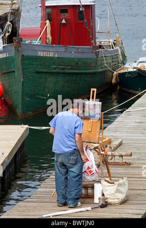 Artist paints tugboat at dock in Rocky Neck artists colony, Gloucester, Massachusetts, USA Stock Photo