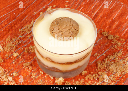 Close-up of vanilla custard and amaretto dessert served in a glass cup over an orange background. Selective focus. Stock Photo