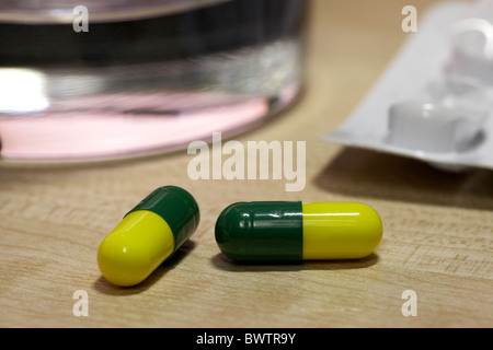 cold and flu remedy capsules with glass of water under artificial office lighting Stock Photo