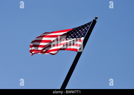 American flag blowing against blue sky Stock Photo