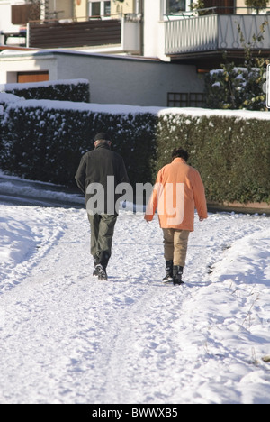 Couple walking on snow covered road Stock Photo