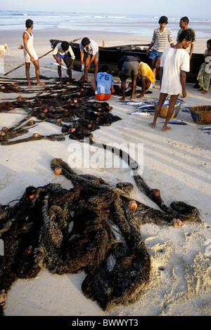 Goa India - Men preparing their fishing nets at dawn, Colva Beach, Goa, India. Stock Photo
