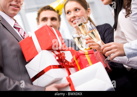 Image of wrapped giftboxes in male hands with cheering friends on background Stock Photo