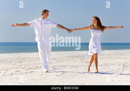 A romantic middle aged coupe dancing holding hands on a deserted tropical beach Stock Photo