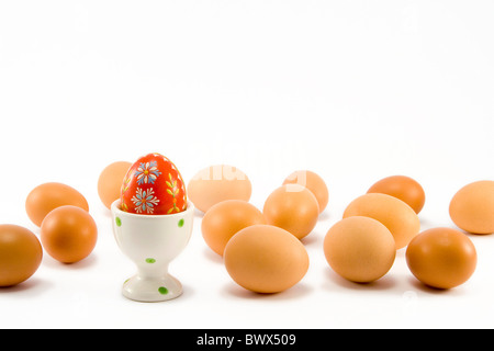 the hand painted red egg in egg-cup among natural eggs Stock Photo