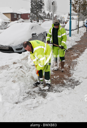 Sidewalk cleared by road worker in special attire, removing snow