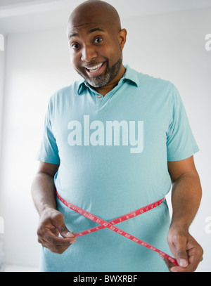 Happy African American man measuring his waistline Stock Photo