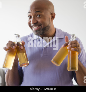 Smiling African American man holding beer bottles Stock Photo