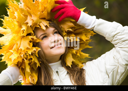 Portrait of smiling young woman wearing wreath of maple leaves Stock Photo