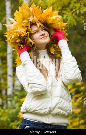 Portrait of smiling young woman wearing wreath of maple leaves Stock Photo