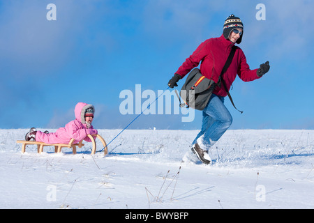 Woman pulling infant girl on wooden sled in winter landscape, Dobel, Black Forest, Gerrmany Stock Photo