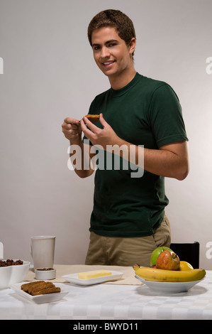 Man having breakfast, spreading butter on a toast Stock Photo