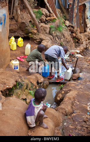 Boys filling containers with water from a tap in the Kibera slums, Nairobi, Kenya Stock Photo