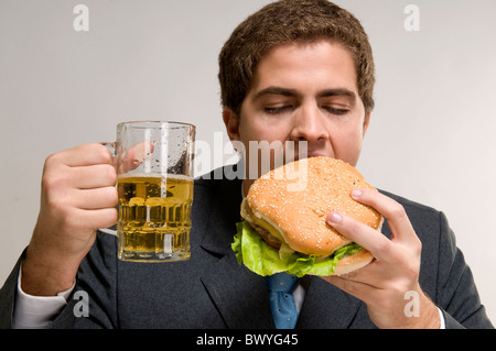 Man eating a hamburger and drinking beer Stock Photo