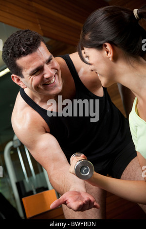 Middle Eastern man helping woman lift weights Stock Photo