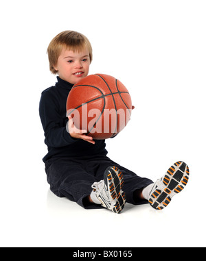 Boy with Down Syndrome playing with basketball over white background Stock Photo