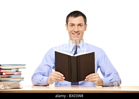 A student reading a book, with many other books on the desk Stock Photo